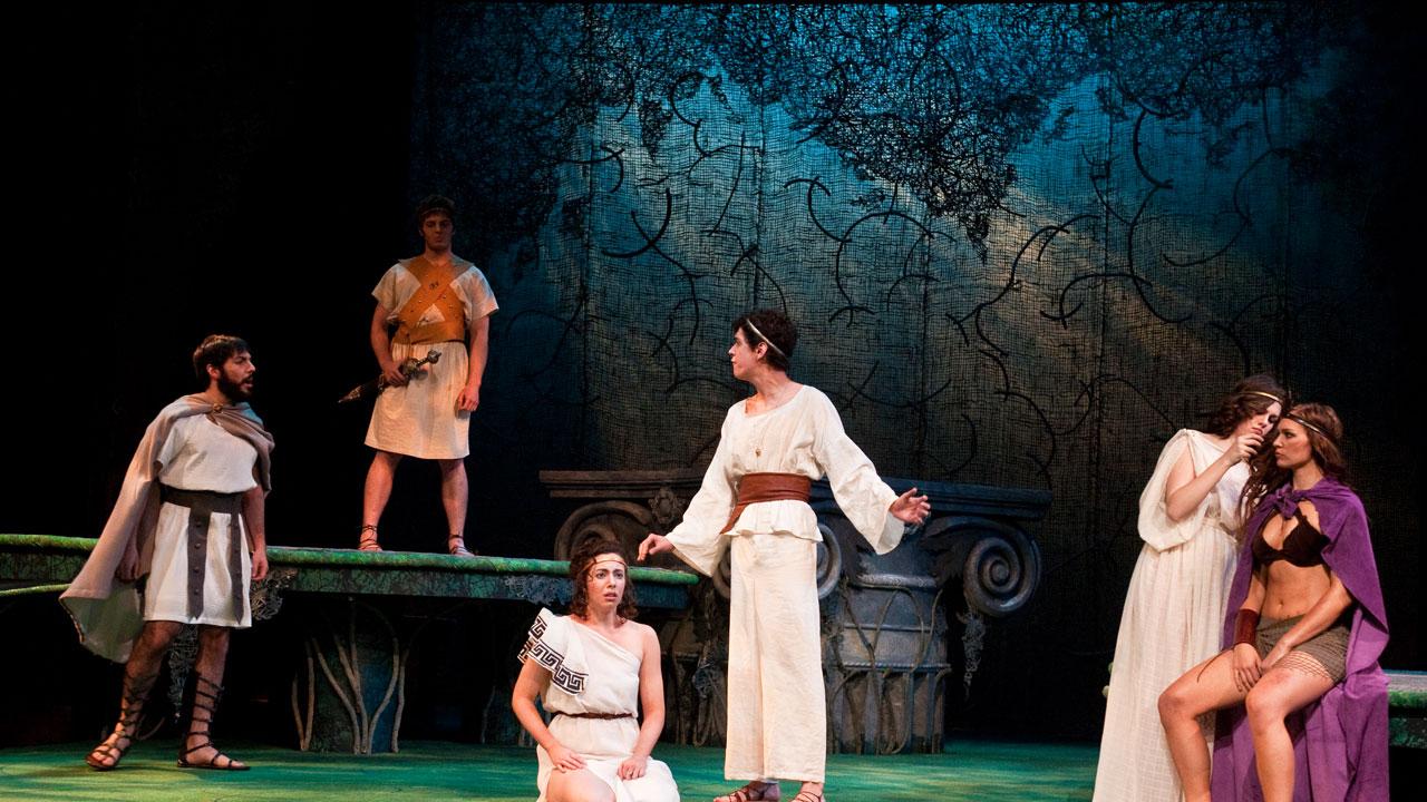 UE Theatre students on stage during a performance wearing ancient Greek themed costumes.